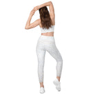 Back view of a white-skinned girl showing her cropped workout bra and beautiful white light-patterned yoga pants with a double-layered flat front waist.  She is also wearing white tennis shoes to match her white athletic pants, with her hands above her head in a yoga stretch pose.