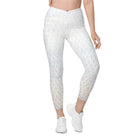 A front view of a white-skinned girl shows her beautiful white light-patterned yoga pants. The garment features a double-layered, crossover waist design, and the photo is against a white background. Her hands are on her hips, and the image is cropped from her stomach. She also wears white tennis shoes and white athletic pants.