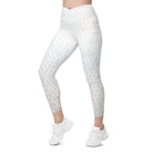 A cropped view of a white-skinned girl shows her beautiful white light-patterned yoga pants. The garment features a double-layered, crossover waist design, and the photo is against a white background. Her hands are not seen, and the image is cropped from her stomach. She also wears white tennis shoes and white athletic pants.