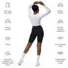 A dark-skinned girl wearing a cropped, long-sleeved workout top with a white light pattern with jeans and white shoes against a white wall showing the back of her yoga top. Icons surrounding the image display a cover-stitched collar, raglan sleeves, a tear-away label, and a fitted, double-layered waistband.