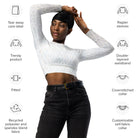 A dark-skinned girl wearing a cropped, long-sleeved workout top with a white light pattern with jeans and white shoes against a white wall showing the front of her yoga top. The image's icons display a cover-stitched collar, raglan sleeves, a tear-away label, and a fitted, double-layered waistband.