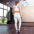 A picture of a girl standing against a mirror with a jump rope. She is wearing lovely white yoga leggings (shown from the back) with a double-layered waist and the white leggings have subtle check patterns. She is also wearing light blue tennis shoes standing on a wooden floor.