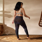 Girl standing on a tan wicker mat, wearing a tan swimsuit top, wearing Salt Skins Flat Front Yoga Workout Pants with a subtle multicolor fleck of purple and red color pattern.