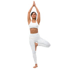 This full-length front view of a girl wearing tight white yoga leggings with beautiful subtle check patterns in the performance fabric. The leggings have a double-layered waist. The black-haired woman is doing yoga, her hands clasped together, pointing up over her head.