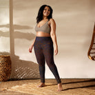 Girl standing on a tan wicker mat, wearing a tan swimsuit top, wearing Salt Skins Flat Front Yoga Workout Pants with a subtle multicolor fleck of purple and red color pattern.